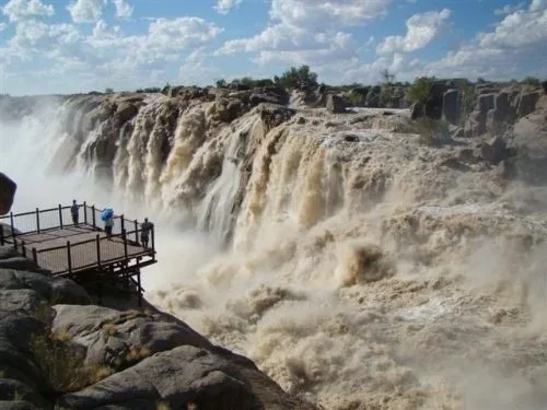 Tourists on a jetty viewpoint looking across to Augrabies Falls and the river gorge below