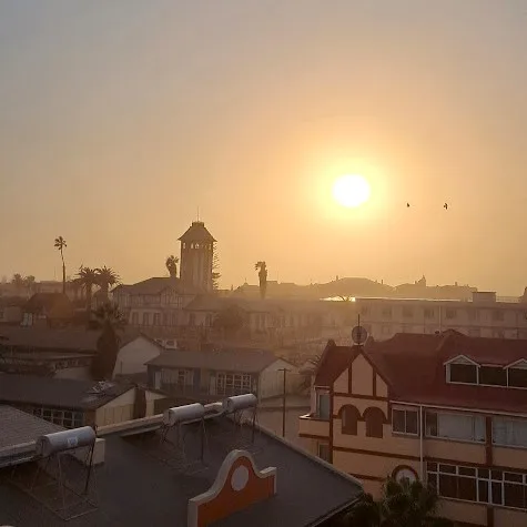 View across the Swakopmund rooftops and the Damara Tower with the sun setting in the distance
