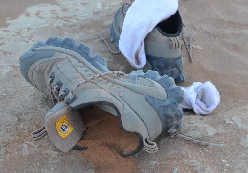 Sand pouring from Caterpillar hiking boots onto the ground during a soft adventure tour
