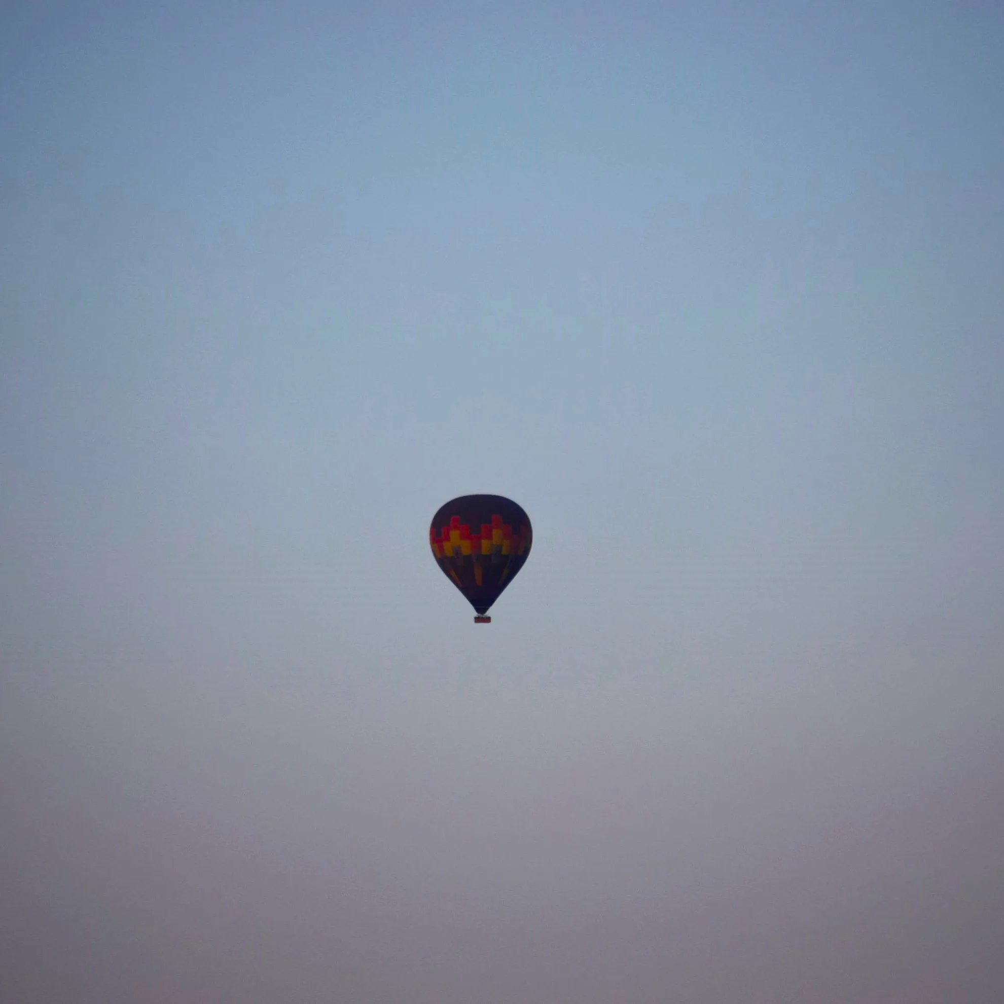 Hot air balloon ascending into the early morning sky above the Namib at the moment of first light