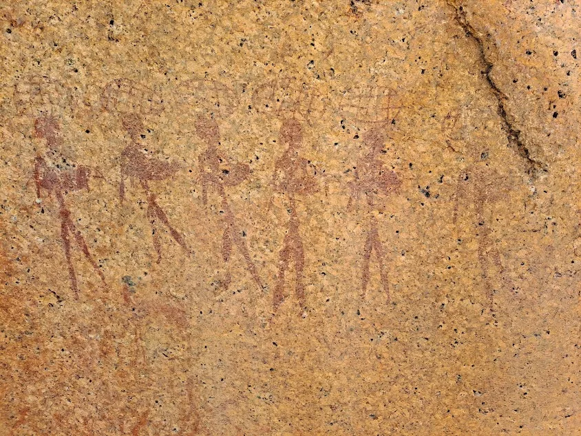 Ancient Khoisan rock art painted in crimson on an orange sandstone rock face