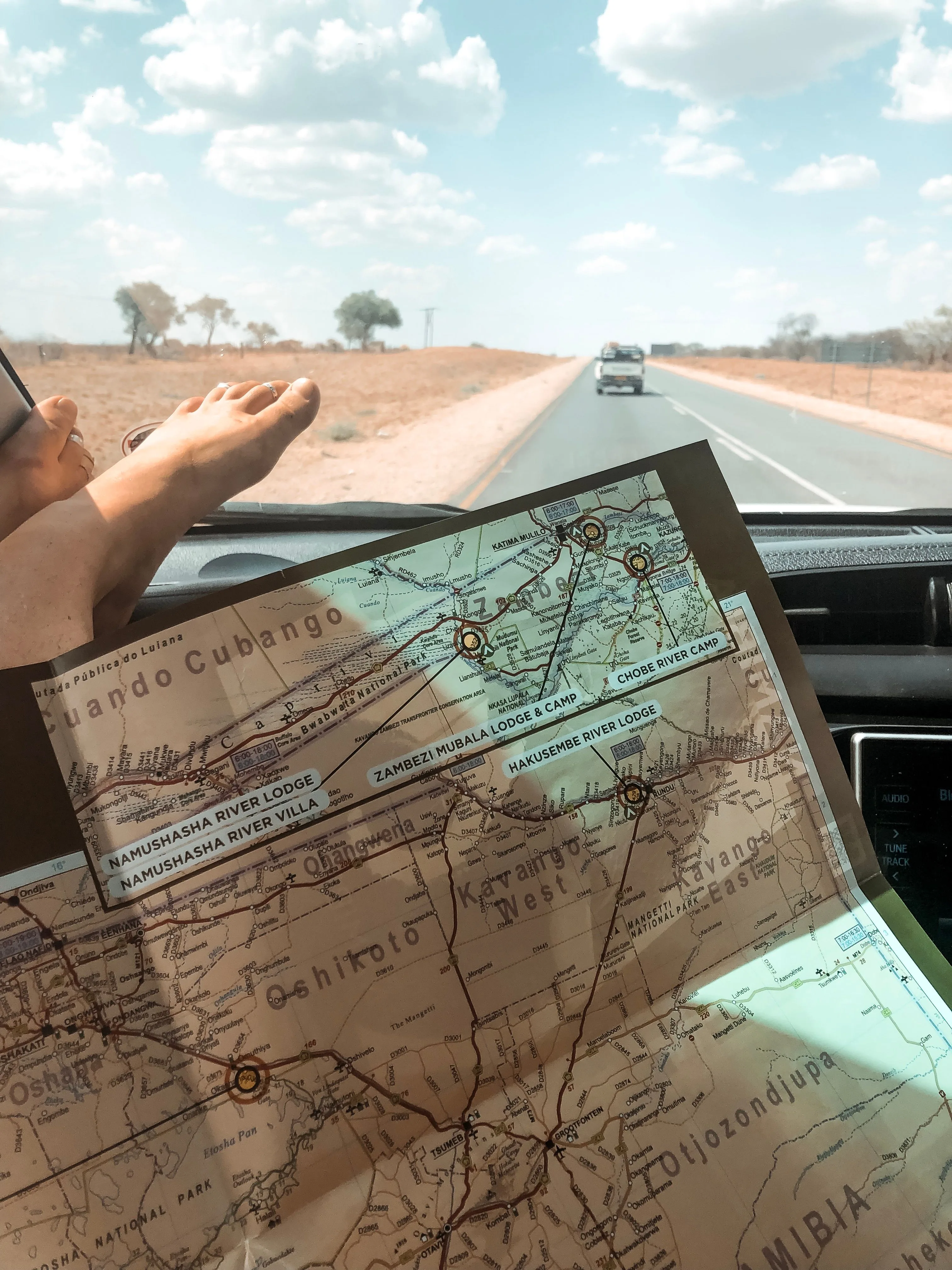 A 4x4 vehicle travelling along a Namibian gravel road through open desert terrain