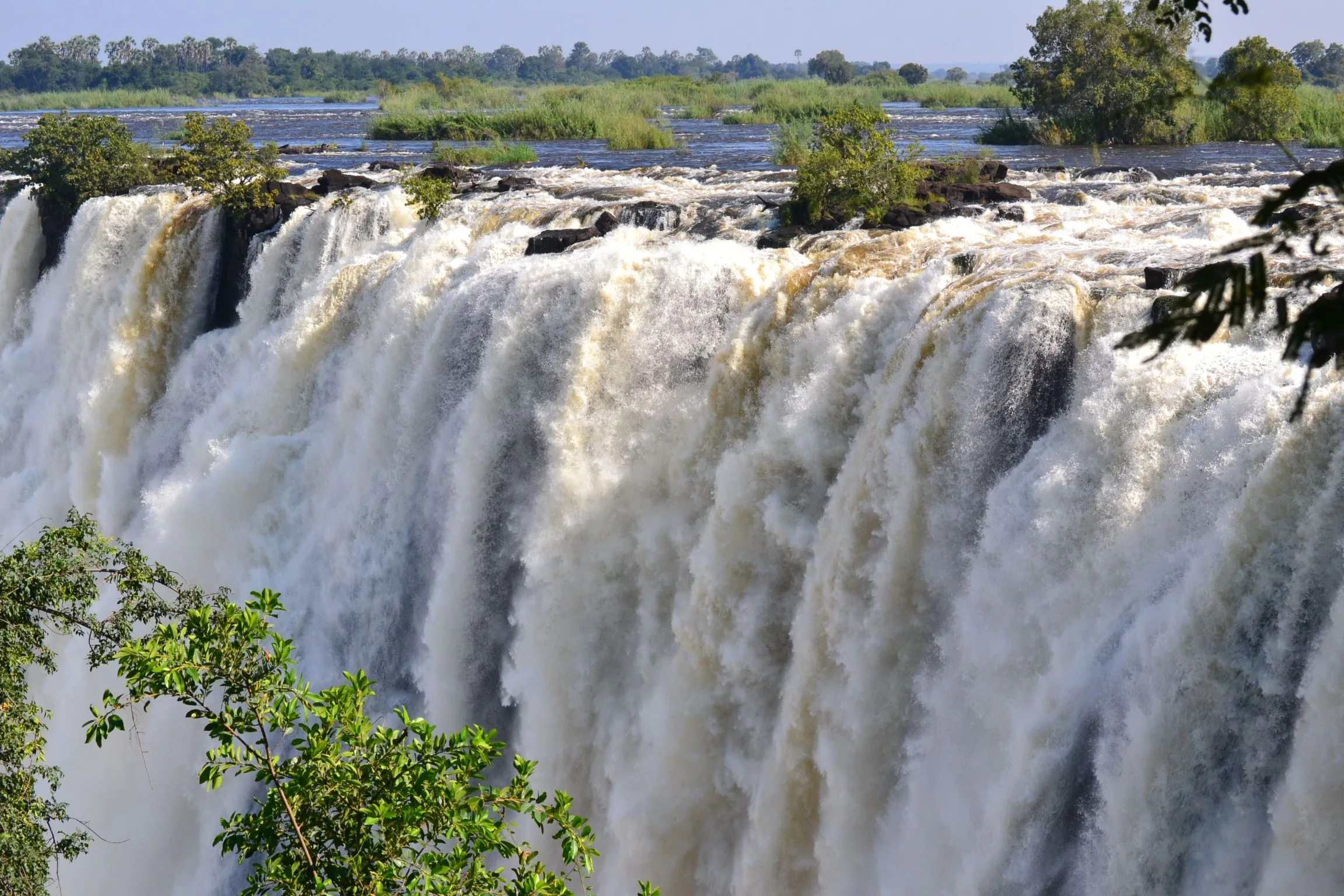 Side view from above of the Zambezi River as it rushes over the basalt cliff face at Victoria Falls in high-water season